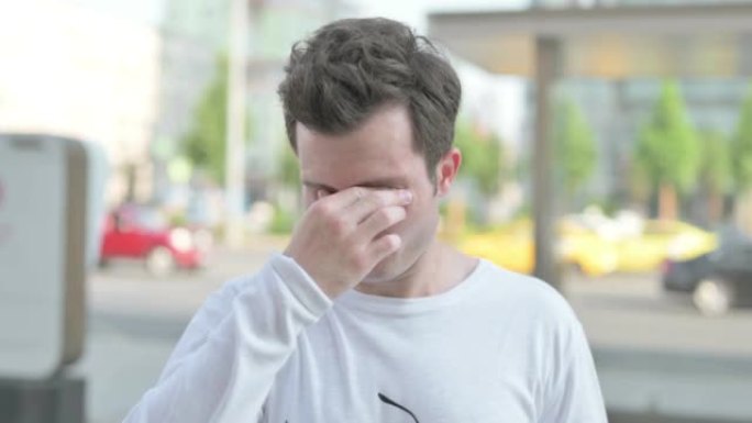 Portrait of Tired Young Man Rubbing Eyes Outdoor