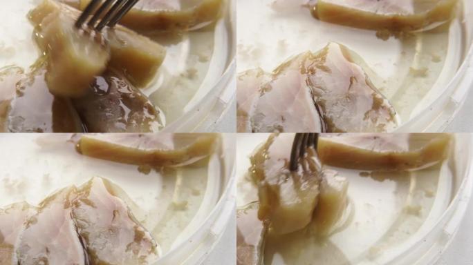叉子在油中刺痛鲱鱼。油酱鱼鲱鱼。切碎的鲱鱼作为主菜的开胃菜。海鲜是在超市买的。
