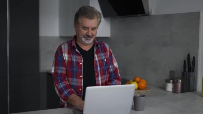 大胡子老人在厨房里使用笔记本电脑