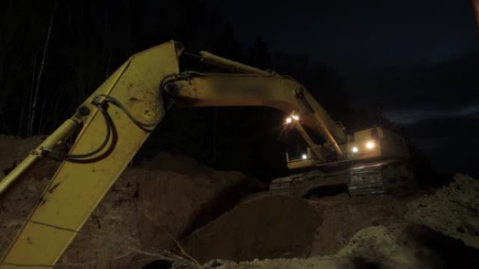 挖掘机在晚上挖一条带前灯的沟渠。晚上工作。夜班施工。工作和休息模式，安全，行业。