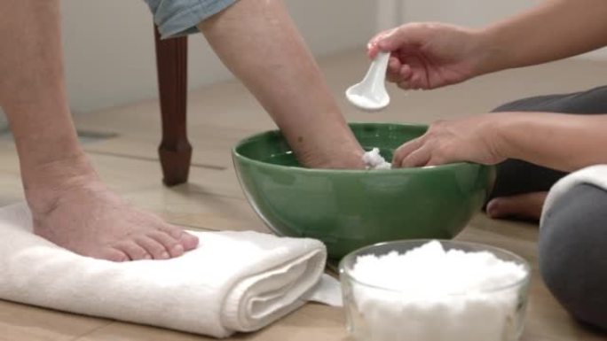 女性护理员用生理盐水按摩和清洁老年妇女的脚。