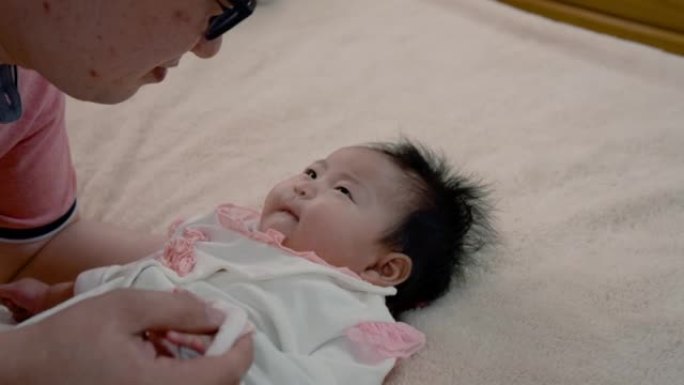 4K，慢速，帅气的亚洲爸爸穿着粉色衬衫，和宝贝女儿躺着调侃，在一张柔软的棕色床上，爸爸温柔地邀请小男