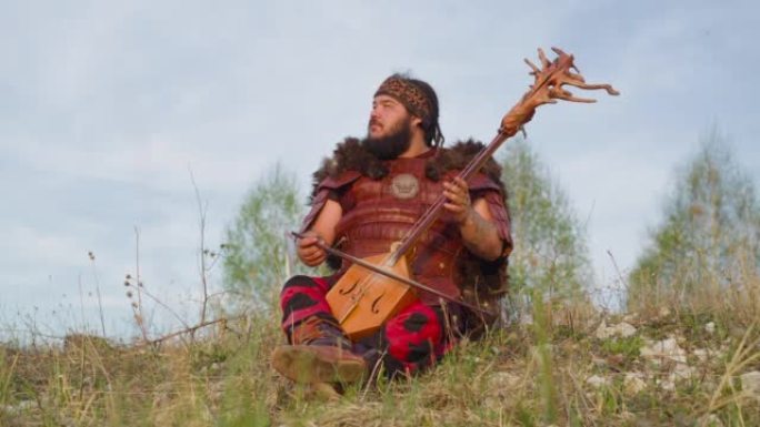 做梦的人坐在山上的草地上演奏弦乐器
