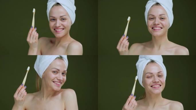 一位美丽的年轻女子，头上挂着一条白毛巾，微笑着用牙刷和牙膏摆姿势。美丽的微笑和洁白的牙齿。医疗保健的