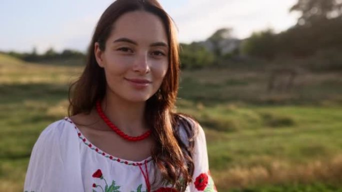 乌克兰年轻微笑女子的肖像，穿着传统的民族刺绣衬衫和草地上的项链。
