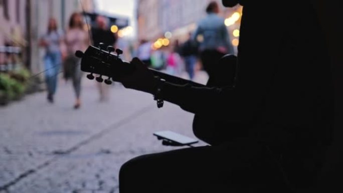 年轻的男性街头音乐家在欧洲城市老城区的门户阴影中弹奏原声吉他
