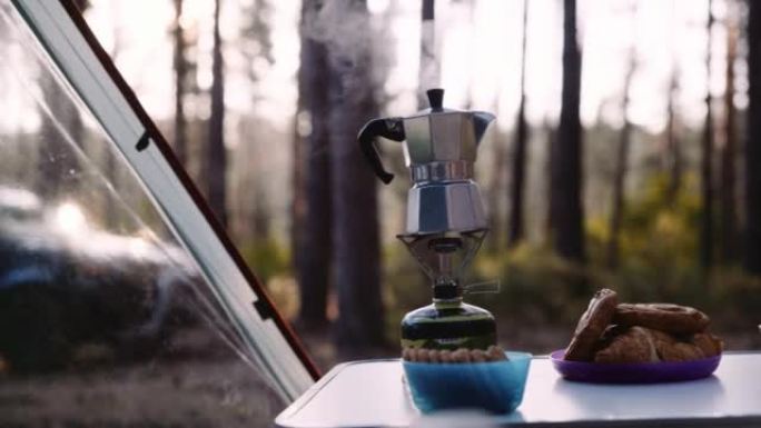 日落时在大自然的露营地喝咖啡。树林里的帐篷。