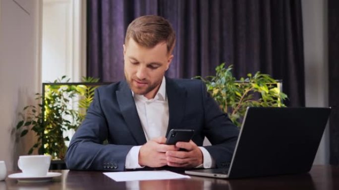 专注的商人，企业家用笔记本电脑在手机上打字，做分析和研究。年轻的男性专业人员坐在餐厅里使用文件。忙碌