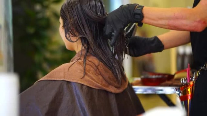 男性美发师在女性头发上使用药物