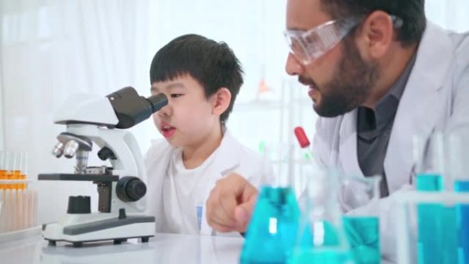 年轻的科学家孩子和老师一起在现代实验室里通过显微镜看。看玻璃板上的样品。教育和学习理念。与高科技合作
