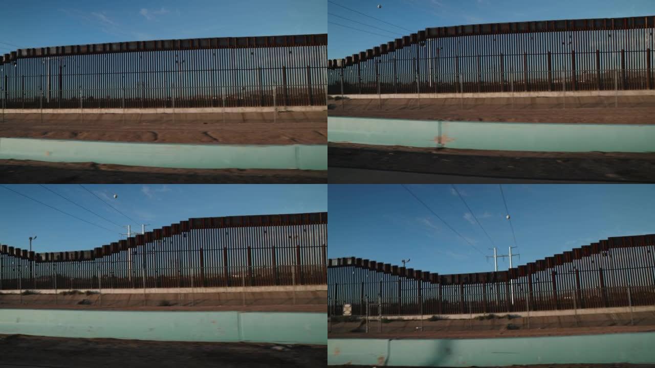 在美国和墨西哥之间的隔离墙旁边行驶的车辆