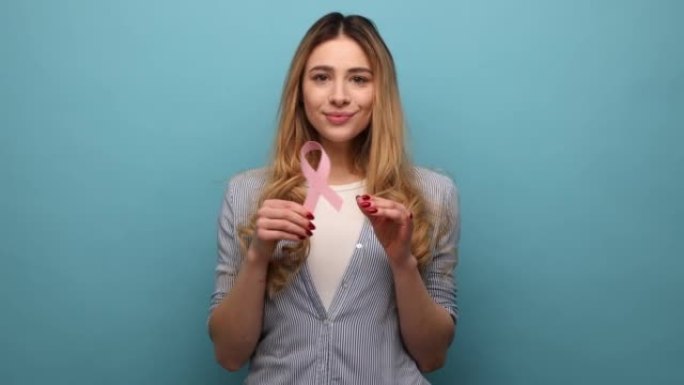 美丽的年轻女子手持粉色丝带，象征乳腺癌，支持肿瘤患者。