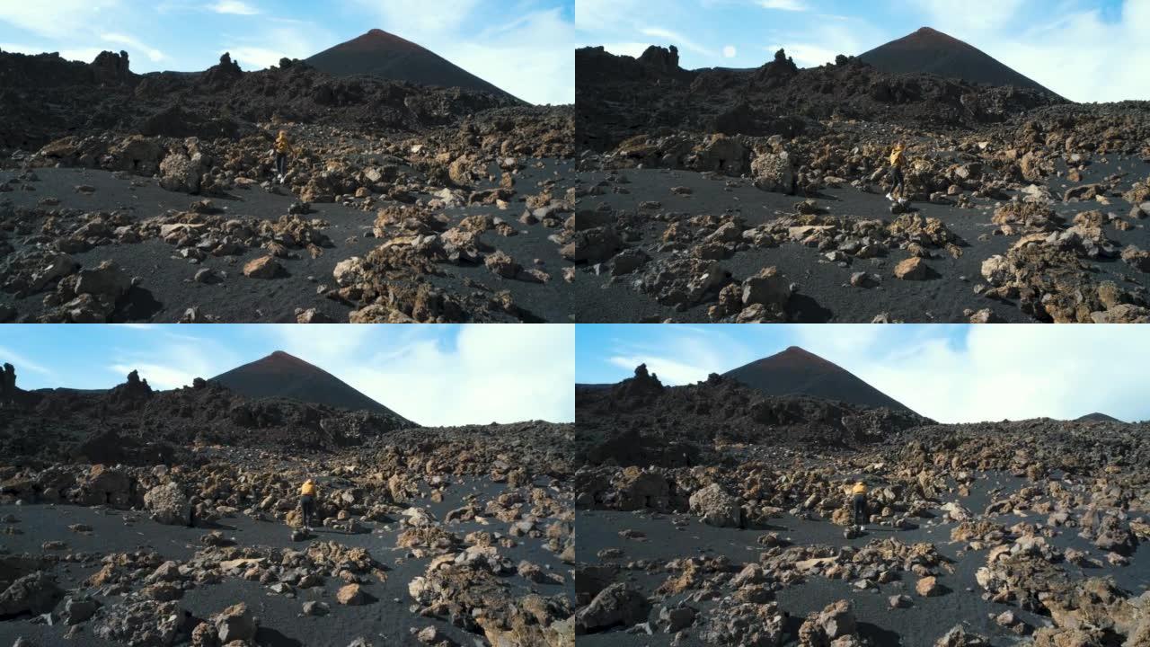 女旅行者在特内里费岛泰德国家公园的钦耶罗火山周围的熔岩田野中漫步。去任何地方。另一个星球的表面。慢动