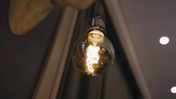 A cool incandescent light bulb hangs on a wire ill
