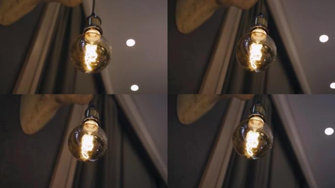 A cool incandescent light bulb hangs on a wire ill