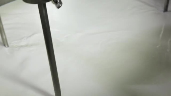 Mixing milk in a cheese factory in a large vat.