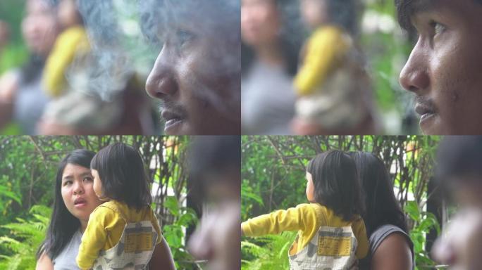 父亲在妻子和孩子附近抽烟。