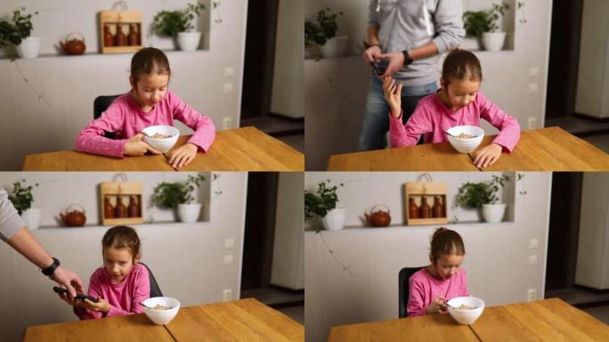 小女孩吃麦片加牛奶，拿着手机在智能手机上玩游戏