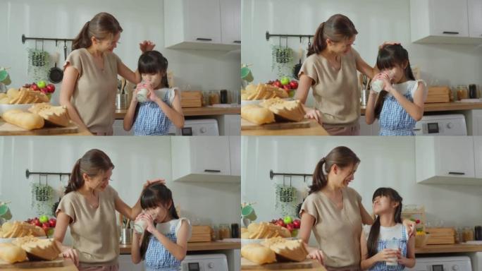 亚洲小可爱抱着一杯牛奶和妈妈一起喝酒。迷人的妈妈教导和支持年轻的女孩女儿照顾她的身体，醒来后在家里接