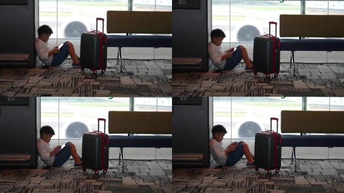 亚洲男孩带着行李在机场候机楼等候