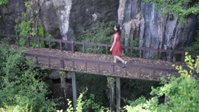 亚洲背包客快乐地走在森林前景热带雨林的木制吊桥上