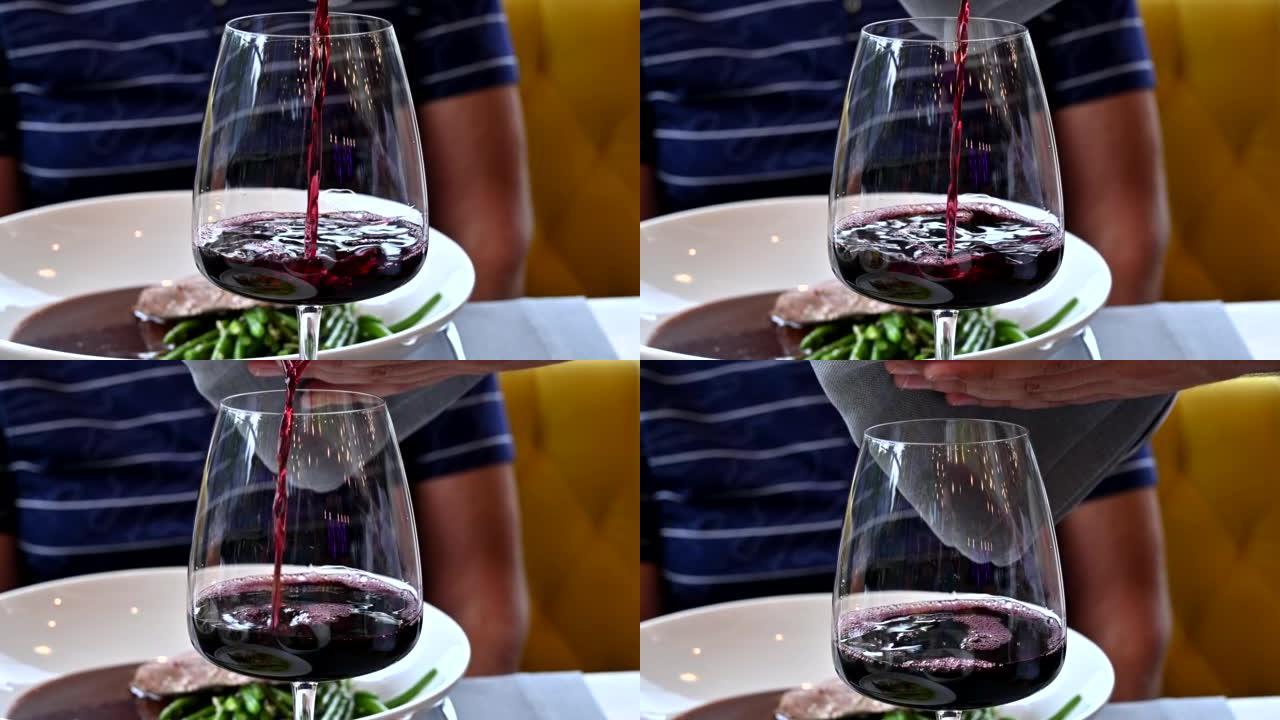 服务员在餐厅将红酒倒入玻璃杯中