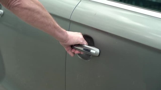 男人的手打开和关闭灰色车门的特写视频。慢动作