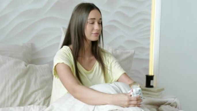 拉西早晨肖像微笑的快乐女人用假肢坐在家里的床上，残疾女孩用假肢。