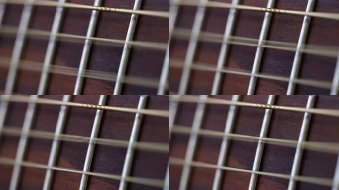 木制吉他的棕色指板上的琴弦振动