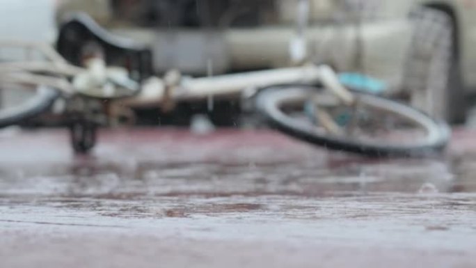 模糊的焦点自行车在雨天发生交通事故后坠落在汽车前的道路上