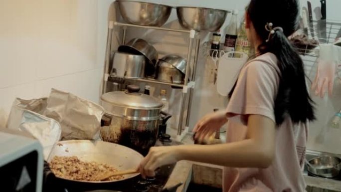 亚洲女孩在家厨房的炉子上做饭，周末生活方式的概念。