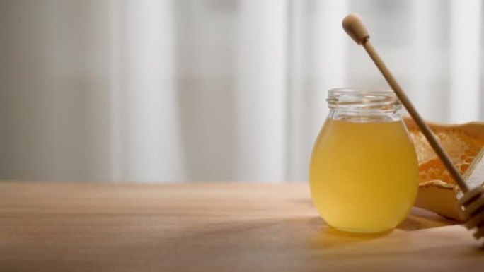 蜂蜜背景。玻璃罐中的甜蜜糖和木桌上的蜜勺。