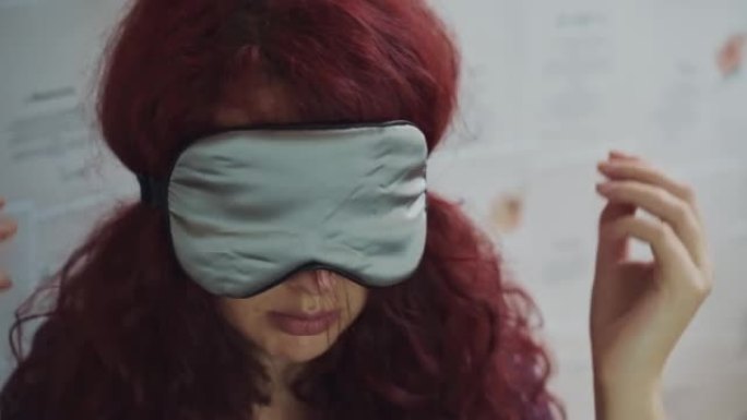勃艮第卷发的女人戴着丝绸睡眠面具。