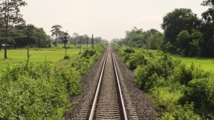 火车轨道上运行的火车的后视图。泰国乡村和热带地区。东南亚的氛围和感觉。新鲜的自然。