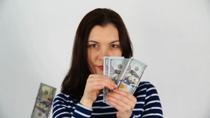 一个黑发女孩，30-35岁，叙述并扔掉钱。百元窗帘散落下来。在白色背景上拍摄。