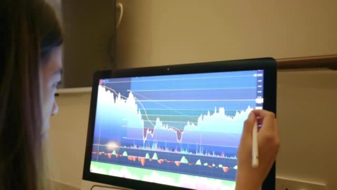 年轻的亚洲投资金融分析师在她的电脑上使用钢笔绘制趋势线加密在证券交易所市场工作