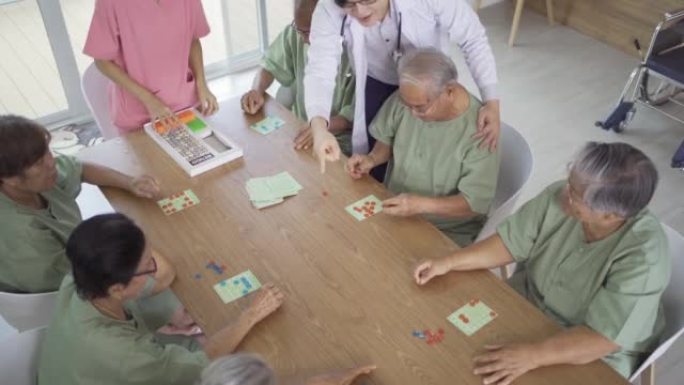 老年亚洲患者或养老金领取者的快乐群体肖像，护士和医生在疗养院玩游戏。高级生活方式活动娱乐。退休社区。