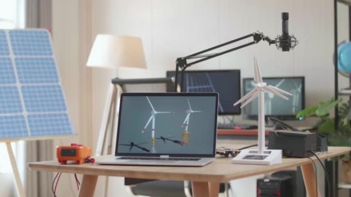 笔记本电脑在办公室太阳能电池旁边的桌子上显示风力涡轮机