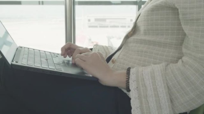 东南亚商务女性在国际机场等待她的航班和在笔记本电脑上工作