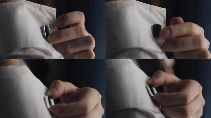 该名男子用手指触摸衬衫袖子上的纽扣。特写他的手