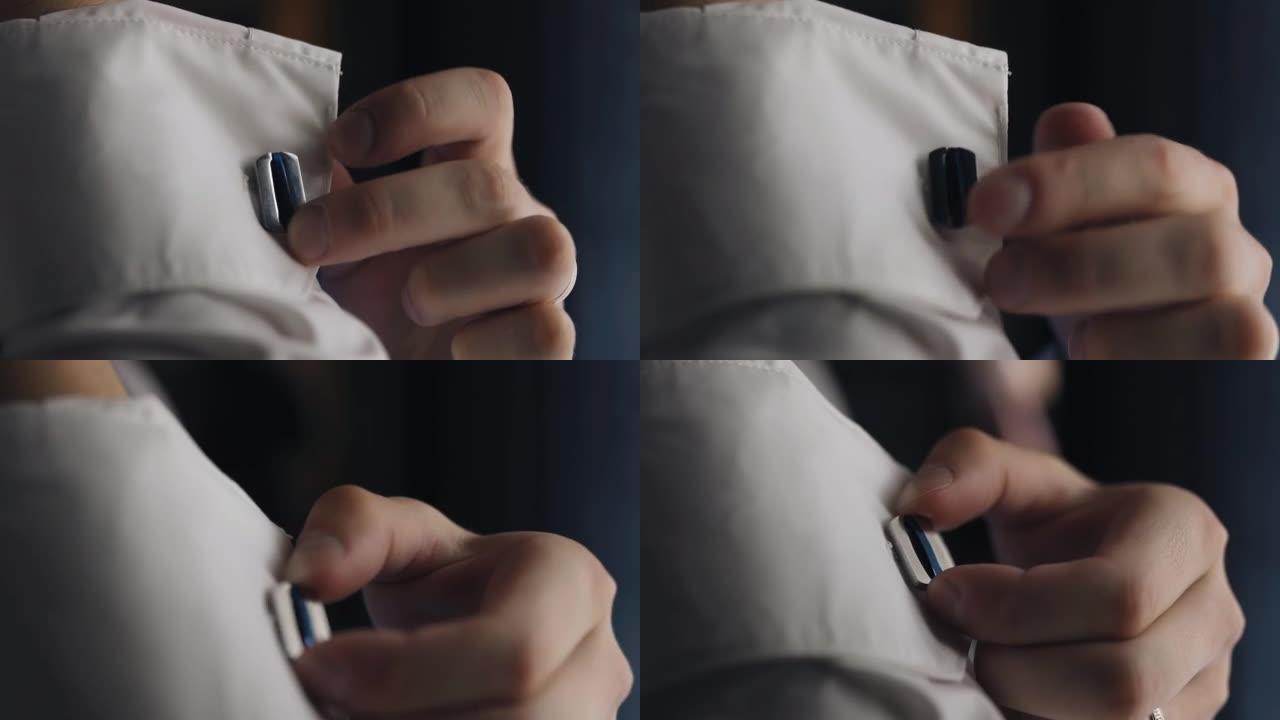 该名男子用手指触摸衬衫袖子上的纽扣。特写他的手