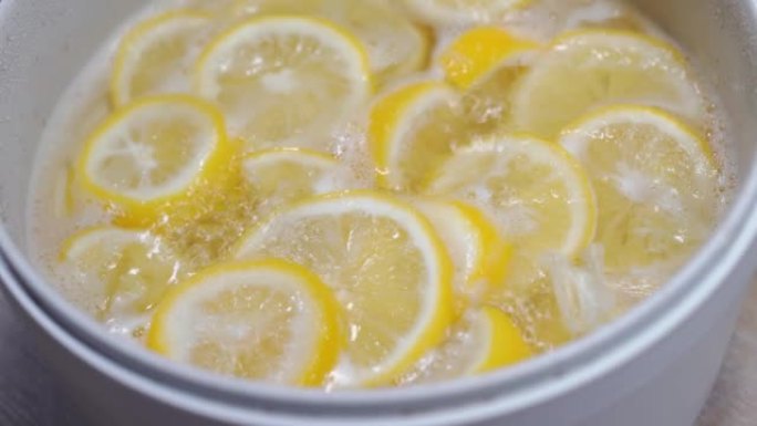 4k镜头特写在电锅中用沸腾的糖浆煮柠檬，用于制作蜂蜜柠檬苏打