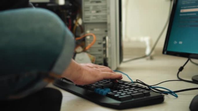 程序员坐在地板上，按下他面前的键盘按钮。他从事电脑编程