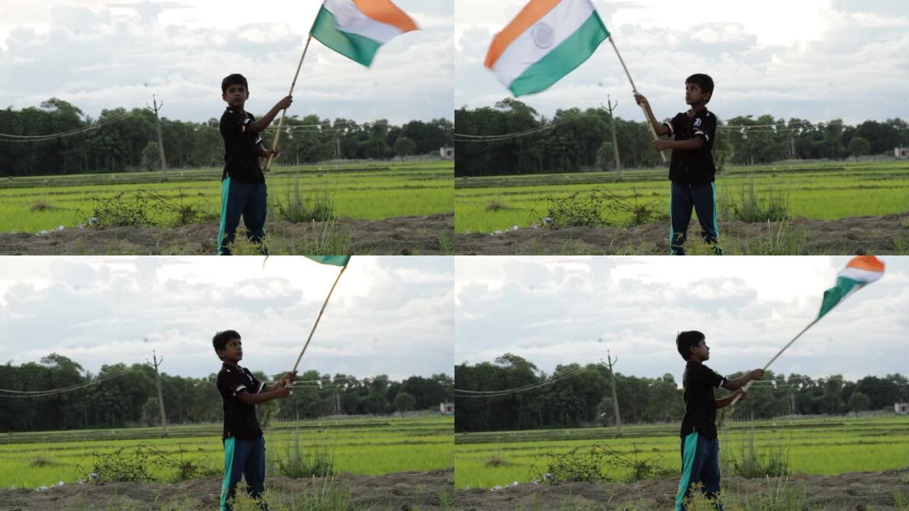 小男孩在大自然中举着三色印度国旗，在空中挥舞着国旗。独立日-假日和共和国日