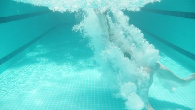 蓝色游泳池，水下拍摄，晴天。胖乎乎的女孩跳进水里。慢动作