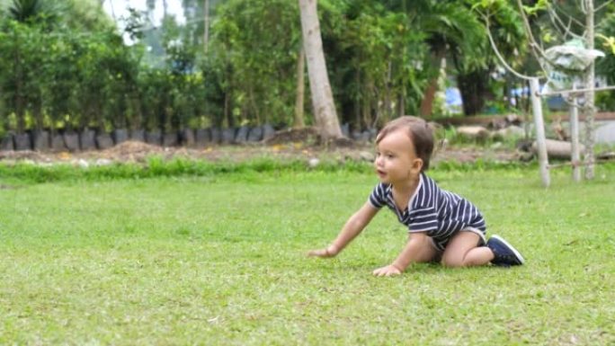 可爱的婴儿学习走路，在公园的草坪上迈出第一步。