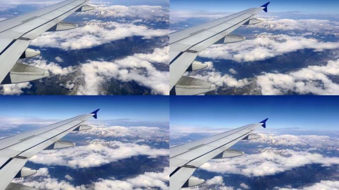 空中客车A320飞机机翼的乘客视角在阿尔卑斯山上空的蓝天中高飞。旅行和航空运输概念
