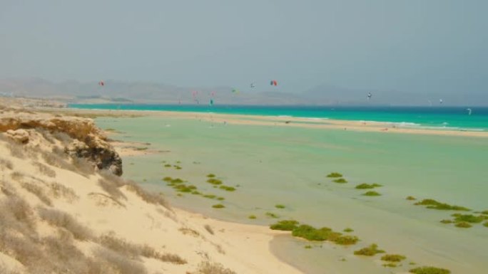 在野生白色沙滩的蓝天前降落伞。游客在天堂岛享受滑翔伞体验。无法识别的人飞行，滑翔伞体验
