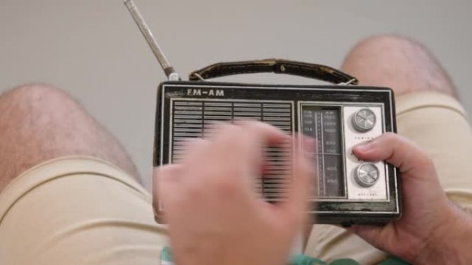 男子在便携式老式收音机上寻找电台并调节音量