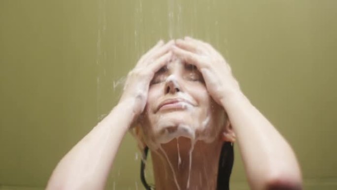 年轻女子淋浴时在脸上涂抹清洁泡沫